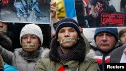 Pro-European integration supporters with taped mouths attend a rally against newly approved anti-protest laws in Kyiv, Jan. 17, 2014.