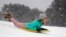 Finley Bork, 7, uses a boogie board, typically used on the beach, for sledding down a hill on a golf course at the Isle of Palms, South Carolina.