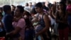 Mujeres venezolanas con sus niños en brazos esperan para alimentarse de forma gratuita en el refugio "Divina Providencia", en Cúcuta, Colmbia en febrero de 2019.