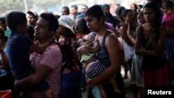 Mujeres venezolanas con sus niños en brazos esperan para alimentarse de forma gratuita en el refugio "Divina Providencia", en Cúcuta, Colmbia en febrero de 2019.