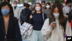 People wearing face masks to help curb the spread of the coronavirus walk at the Ginza shopping district on Tokyo, Janpan, Nov. 8, 2021.