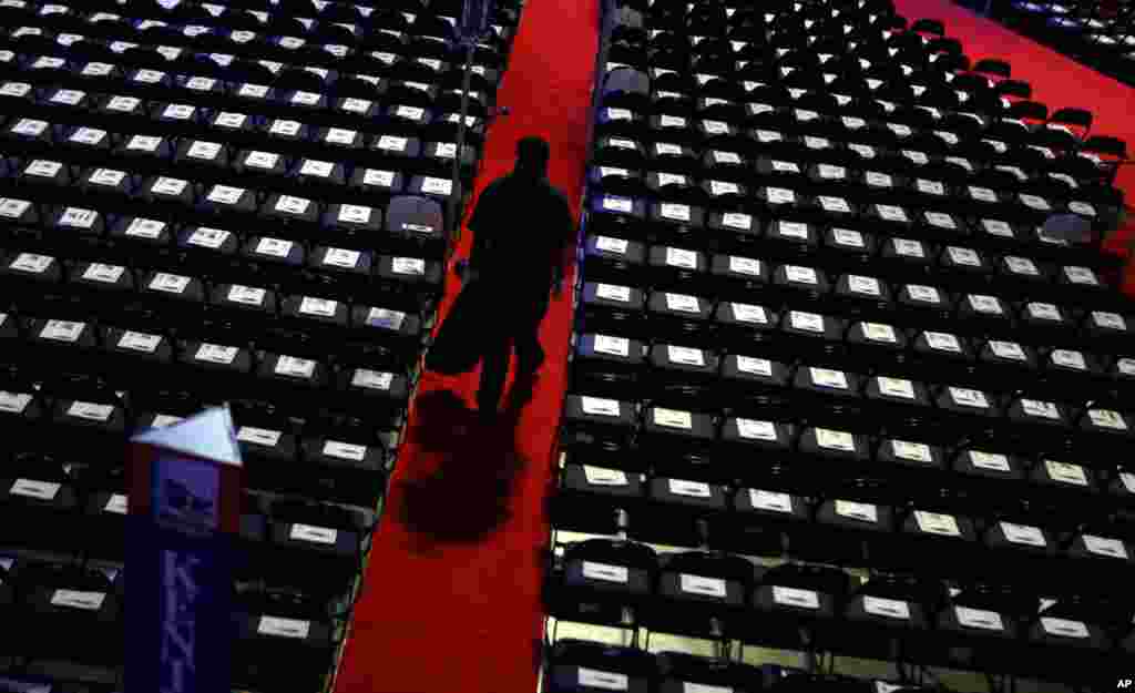 A worker walks down the aisle to collect trash on the floor at the convention.