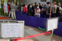 FILE - In this Wednesday, March 24, 2021 file photo, a notice of vaccine suspension, left, is placed as people queue up outside a vaccination center for BioNTech in Hong Kong. Hong Kong's sudden suspension of a COVID-19 vaccine developed by Pfizer…