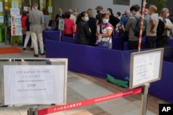 FILE - In this Wednesday, March 24, 2021 file photo, a notice of vaccine suspension, left, is placed as people queue up outside a vaccination center for BioNTech in Hong Kong. Hong Kong's sudden suspension of a COVID-19 vaccine developed by Pfizer…
