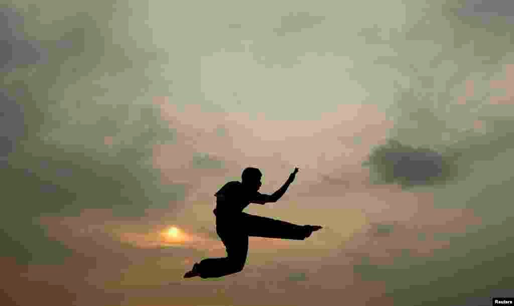 Un niño practica karate en la playa y su silueta en el aire vuela en contra del atardecer en Colombo, Sri Lanka.