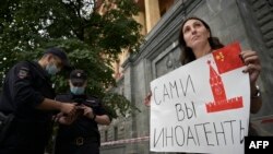 A journalist holds a placard which reads "Foreign agents yourself" during a single picquet of solidarity with collegues who was added to the list of "foreign agent" media near the headquarters of Russia's Federal Security Service (FSB) in Moscow on August