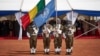 Des soldats brandissent les drapeaux de l'ONU et du Mali lors de la cérémonie de la Journée des Casques bleus à la base opérationnelle de la Minusma à Bamako, le 29 mai 2018.