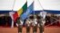 FILE - Soldiers hold the United Nations and Malian flags during the ceremony of Peacekeepers Day at the operating base of MINUSMA (The United Nations Multidimensional Integrated Stabilization Mission in Mali) in Bamako on May 29, 2018.