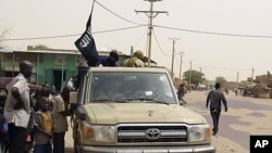 Fighters from the Ansar Dine group, flying the group's black flag, instruct local residents in how to follow Shariah, as they stop in a market area of Timbuktu, Mali, April 14, 2012. 