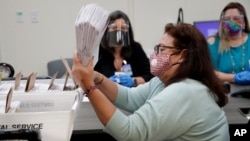 La trabajadora del Departamento de Elecciones de Miami-Dade, Elizabeth Romero, ordena boletas de votación enviadas para las primarias del 18 de agosto.