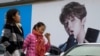 FILE - Women walk past an ad featuring teen idol Lu Han in Beijing, Oct. 21, 2017. China's government banned effeminate men on TV and told broadcasters Sept. 2, 2021, to promote "revolutionary culture." 