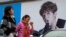 FILE - Women walk past an ad featuring teen idol Lu Han in Beijing, Oct. 21, 2017. China's government banned effeminate men on TV and told broadcasters Sept. 2, 2021, to promote "revolutionary culture." 