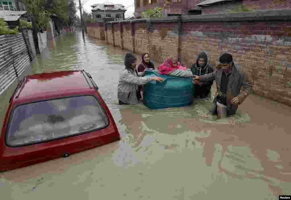 People transport a sick woman in an empty water tank on a flooded street during rain in Srinagar, Sept. 5, 2014.