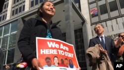 Erica Leyva muestra un cartel que dice "Estamos para quedarnos", durante una protesta frente al tribunal en San José, California donde se han escuchado argumentos retando el decreto de Trump sobre ciudades santuario.