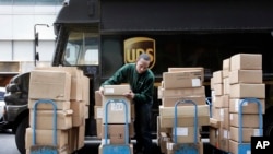 FILE - A UPS driver unloads packages from a truck and arranges them for delivery in New York.