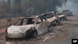 FILE - The burned out hulks of cars abandoned by their drivers sit along a road in Paradise, Calif., Nov. 9, 2018. 