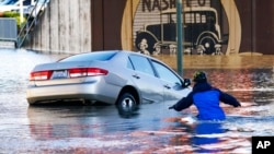 FILE - Kenneth Warner races to help rescue the driver of a car that went into the flooded Nooksack River, Nov. 16, 2021, in Ferndale, Wash. It's been a weird winter in the United States. The Pacific Northwest has received record rainfall while the Rockies still haven't seen their first significant snowfall.