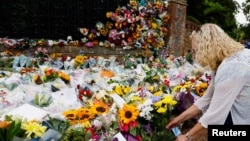 زنی پس از مرگ ملکه الیزابت دوم، در مقابل کاخ ساندرینگهام در شرق بریتانیا گل می‌گذارد - ۱۳ سپتامبر ۲۰۲۲