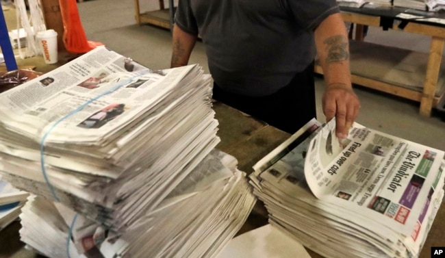 FILE - An employee sorts newspapers for delivery at a distribution center in Liberty Township near Youngstown, Ohio, on Aug. 6, 2019. (AP Photo/Tony Dejak, File)