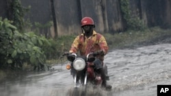 A man ride on motor cycle through a flooded street following a heavy downpour in Lagos, Nigeria, July 11, 2011