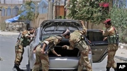 Yemeni army soldiers check a car in Sana'a, Yemen, as government troops try to recapture areas held by Islamic militants, June 9, 2011