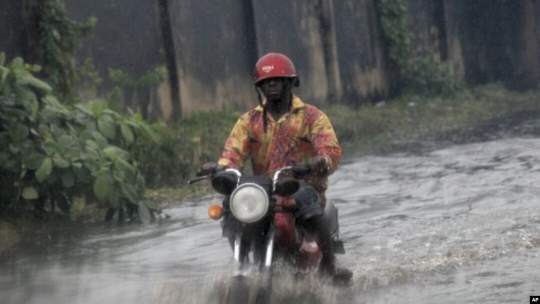A man ride on motor cycle through a flooded street following a heavy downpour in Lagos, Nigeria, July 11, 2011