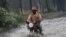 A man ride on motor cycle through a flooded street following a heavy downpour in Lagos, Nigeria, July 11, 2011