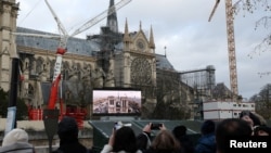 Pessoas numa área pública para assistir à cerimónia de reabertura da Catedral de Notre-Dame de Paris, cinco anos e meio depois de um incêndio ter devastado a obra-prima gótica, em Paris, França, 7 de dezembro de 2024.