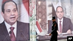 Hamas police officer walks in front of large portraits of Egyptian President Abdel Fattah el-Sissi, while Hamas leaders meet the head of the Egyptian General Intelligence Abbas Kamel, unseen, in Gaza City, May 31, 2021. 