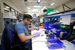 FILE - Skydio tech assembler Alex Nakmoto works on the R1 flying camera drones in a laboratory in Redwood City, Calif., June 22, 2018.