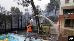 A man throws water from a swimming pool as fire approaches his house in Ippokratios Politia village, about 35 kilometers north of Athens, Greece, Aug. 6, 2021.