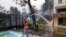 A man throws water from a swimming pool as fire approaches his house in Ippokratios Politia village, about 35 kilometers north of Athens, Greece, Aug. 6, 2021.