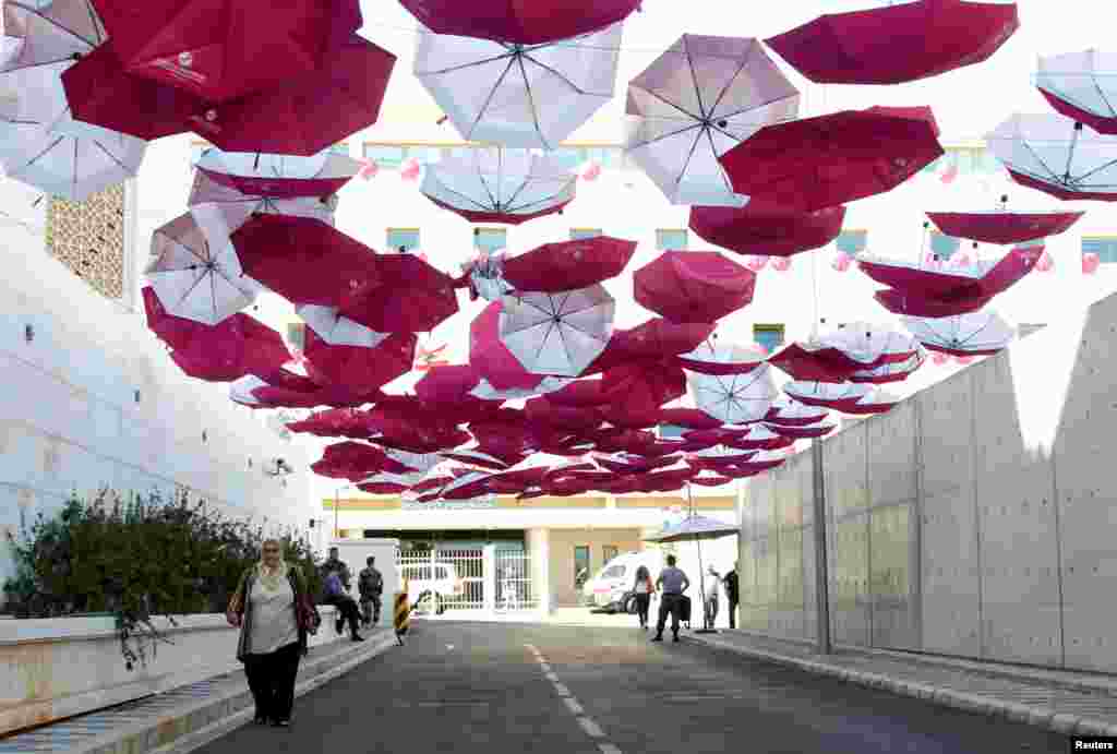 A woman walks under a canopy of umbrellas outside the Ministry of Public Health, part of a campaign aiming at raising awareness of breast cancer prevention, in Beirut, Lebanon.