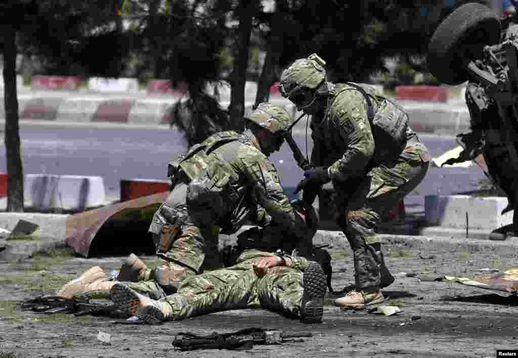 Tentara AS mengurusi seorang prajurit yang terluka di lokasi ledakan di Kabul, Afghanistan. Sedikitnya 17 orang terluka dalam ledakan bom bunuh diri terhadap pasukan NATO ketika iring-iringan truk mereka melewati jalan utama antara bandara Kabul dan Kedutaan Besar AS, menurut polisi dan pejabat kementerian kesehatan.