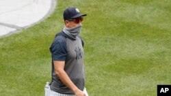 New York Yankees manager Aaron Boone wears a neck gaiter as a mask during a baseball summer training camp workout at Yankee Stadium, July 8, 2020, in New York.