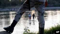 Migrantes hondureños que intentaron ingresar a México a pie regresan al lado guatemalteco del río Suchiate bajo la vigilancia de una Guardia Nacional mexicana cerca de Ciudad Hidalgo. Foto: AP.