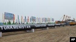 FILE - Workers at the Turkmen-Afghan border prepare to weld the first link crossing the frontier during the integration ceremony of the pipeline in Serhetabat, Turkmenistan, Feb. 23, 2018.