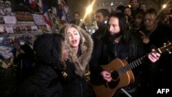 La chanteuse américaine Madonna, au centre, chante à côté de son guitariste Monte Pittman (à sa droite) et son fils David Banda (a gauche), au lieu de la République à Paris à un mémorial improvisé en hommage aux victimes des attaques terroristes à Paris, 10 décembre 2015.