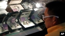 In this March 2, 2015 photo, a Thai visitor examines Rolex watches at the public viewing for an auction of items seized from Lt. Gen. Pongpat Chayapam, in Bangkok, Thailand. 