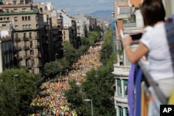 A woman takes photos from a balcony during march to celebrate Catalan National Day in Barcelona, Spain, Sept. 11, 2017.