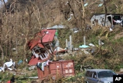 FILE - In this Sept. 23, 2017, photo, homes lay scattered after the passing of Hurricane Maria in Roseau, the capital of the island of Dominica.