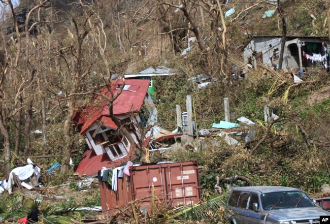 FILE - In this Sept. 23, 2017, photo, homes lay scattered after the passing of Hurricane Maria in Roseau, the capital of the island of Dominica.