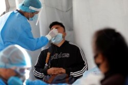 Un trabajador de la salud toma una muestra de la prueba rápida de de COVID-19, en el exterior del estadio Azteca en la Ciudad de México, México, 25 de noviembre de 2020.