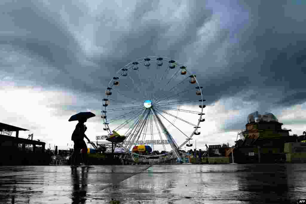 Fair attendees walk past the Ferris wheel as rain begins to fall at the Iowa State Fair on Aug. 8, 2019 in Des Moines, where Democratic 2020 presidential hopefuls were expected to speak.