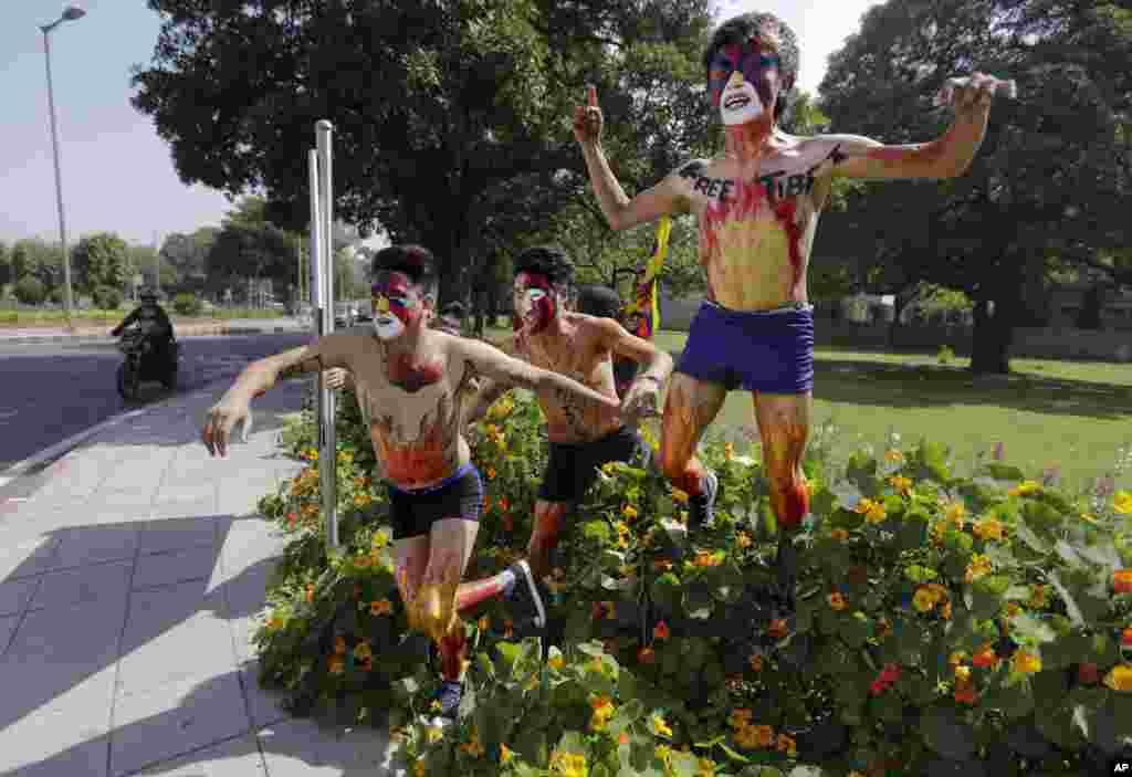 Tibetan exiles, their faces painted in the colors of the Tibetan flag, jump over a flower bed as they make their way toward the Chinese Embassy during a protest in New Delhi, India.
