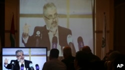Hamas leaders and supporters listen to Khaled Mashaal, the outgoing Hamas leader in exile, during his news conference in Doha, Qatar, while displayed on a screen at Commodore hotel in Gaza City, Monday, May 1, 2017. 