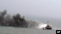 In this image provided by the Italian Navy, a helicopter hovers above the Italian-flagged Norman Atlantic, shown billowing smoke, after it caught fire in the Adriatic Sea, Dec. 28, 2014. 