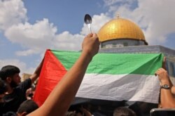 Seseorang memegang sendok, dilaporkan alat penggali yang digunakan oleh enam tahanan Palestina yang melarikan diri dari penjara Gilboa Israel, saat berkumpul di depan masjid Kubah Batu setelah salat Jumat di masjid al-Aqsa Yerusalem. (Foto: AFP)