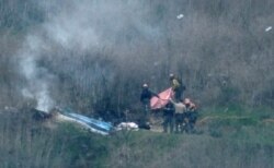 Law enforcement officers investigate the scene of a helicopter crash that killed retired basketball star Kobe Bryant and others, in Calabasas, near Los Angeles, California, Jan. 26, 2020.