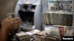 FILE - An employee counts money at an exchange office in downtown Cairo, Egypt, June 5, 2014. 